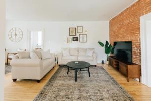 a living room with white furniture and a brick wall at Newly Renovated Vintage Inspired Large 4 BR Home in Mount Joy