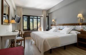 um quarto de hotel com uma cama grande e uma secretária em Hotel Edelweiss Candanchú em Candanchú
