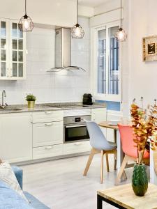 a kitchen with white cabinets and a table and chairs at Charming Puerta del Sol Center - 6 Bedrooms in Madrid