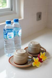 Deux bouteilles d'eau et une assiette de fleurs sur un comptoir dans l'établissement Donguri House Bali, à Jimbaran