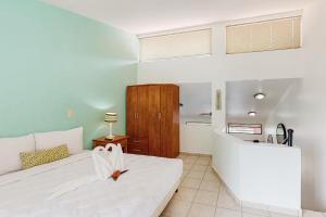 1 Schlafzimmer mit einem weißen Bett und einer Küche in der Unterkunft Flamenco Rosa A13 in Coco