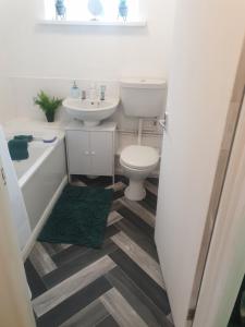 a bathroom with a toilet and a tub and a sink at A&S properties, no guest fees, with drive and near city centre in Wolverhampton +5 photos