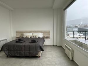 a bedroom with a bed and a large window at Jainen Apartamentos in Ushuaia