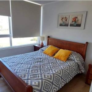 1 dormitorio con 1 cama con 2 almohadas amarillas en Apartment Lomas De Papudo, en Papudo