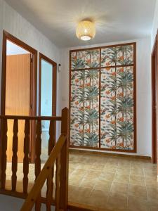ein Flur mit einer großen Glastür mit einem Wandgemälde von Palmen in der Unterkunft Casa frente al mar con Vistas in Oliva + 15 Fotos