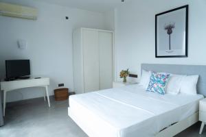 a white bedroom with a large white bed and a desk at Four Petals Inn in Colombo