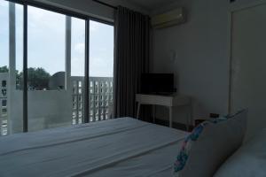 1 dormitorio con 1 cama y balcón con TV en Four Petals Inn, en Colombo