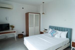 1 dormitorio con 1 cama blanca y TV en Four Petals Inn en Colombo
