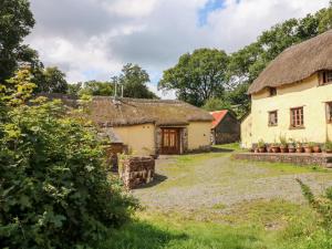 een oude boerderij met een rieten dak bij The Threshing Barn in Beaworthy