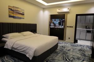 a bedroom with a large bed and a kitchen at قمم بارك النماص Qimam Park Hotel 6 in Al Namas