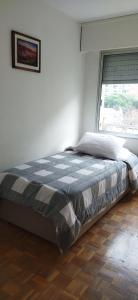 Bett in einem weißen Zimmer mit Fenster in der Unterkunft Apto en Pocitos cerca a La Rambla para 4 personas in Montevideo