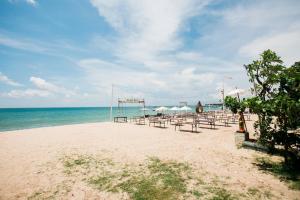 a beach with tables and chairs and the ocean at Donguri House Bali in Jimbaran