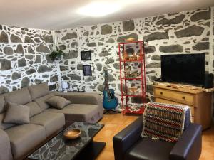 a living room with a couch and a rock wall at Paraiso da Pedreira in Nordeste