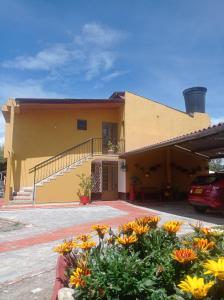 un edificio amarillo con flores delante en Apartamento Campestre la Casa de Leo en Paipa
