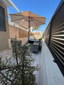 une terrasse avec un parasol, des chaises et une clôture dans l'établissement דירה נאה ומרווחת עם חצר פרטית, à Netanya