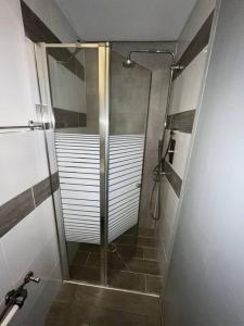 La salle de bains est pourvue d'une douche avec une porte en verre. dans l'établissement דירה נאה ומרווחת עם חצר פרטית, à Netanya