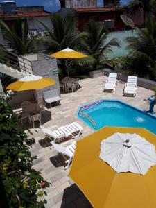 a swimming pool with umbrellas and chairs and a swimming pool at Flat Porto dos Carneiros in Tamandaré
