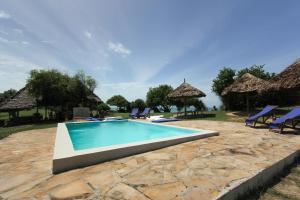 a swimming pool with blue chairs and umbrellas at Pangani Cliffs Lodge in Pangani