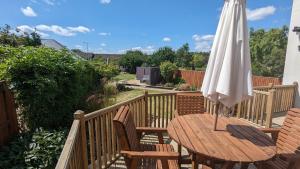 un tavolo in legno con ombrellone su una terrazza di Cheltenham large house with gym, bar & hot tub a Golden Valley