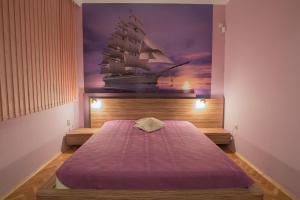 ein Schlafzimmer mit einem Bett mit einem Gemälde eines Schiffes in der Unterkunft Sea Garden Plaza Apartment in Burgas City