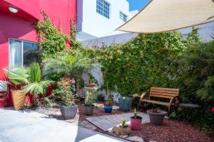 Casa Roja - 1block2beach - Las Playas في تيخوانا: حديقة بها نباتات الفخار ومقعد خشبي