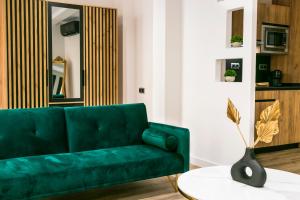 un sofá verde en una sala de estar con mesa en BOUTIQUE REYES CATÓLICOS, en Granada