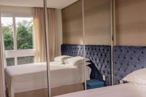 Un dormitorio con dos camas y un espejo. en Morada do Estaleiro, en Balneário Camboriú 49 fotos más