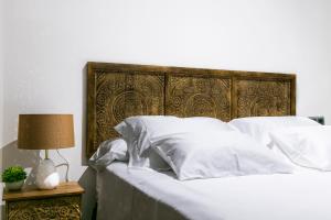 a bed with white sheets and a wooden headboard at BOUTIQUE REYES CATÓLICOS in Granada +11 photos