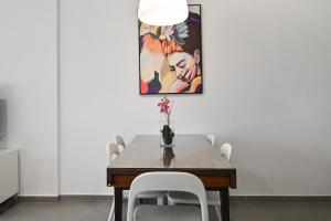 a dining room table with white chairs and a painting at Great 2BR in Lassale street by HolyGuest in Tel Aviv