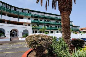 a building with a palm tree in front of a parking lot at FlordeTajinaste in Puerto de la Cruz