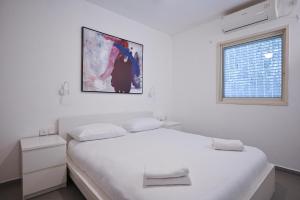 a white bedroom with a white bed and a window at Great 2BR in Lassale street by HolyGuest in Tel Aviv