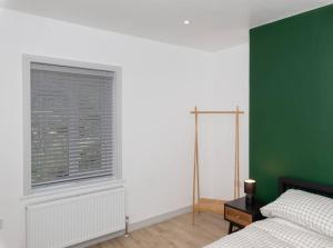 um quarto com uma cama e uma parede verde em Charming Gateshead Retreat - Close to Newcastle - Angel of the North em Sheriff Hill