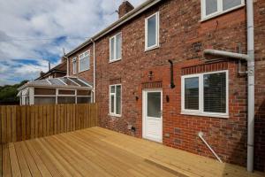 a brick house with a wooden deck in front of it at Charming Gateshead Retreat - Close to Newcastle - Angel of the North in Sheriff Hill