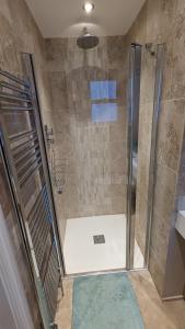 a shower with a glass door in a bathroom at Cheltenham large house with gym, bar & hot tub in Golden Valley