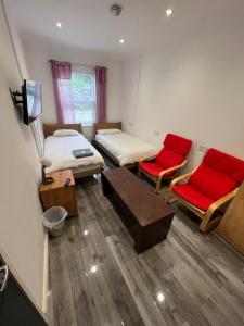 a room with two beds and two red chairs at Zams rooms in Stoke on Trent