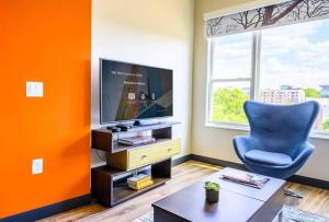 sala de estar de color naranja con silla azul y TV en Private Downtown Apartment With King Bed, en Raleigh