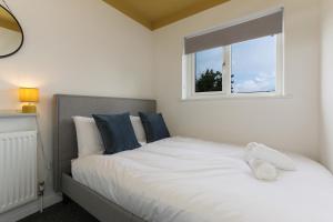 a white bed with blue pillows and a window at City Oaks - Sheffield Station & Utilita Arena in Sheffield