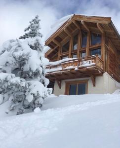 a log cabin in the snow with a snow covered tree at Chalet Loan in Montgenèvre