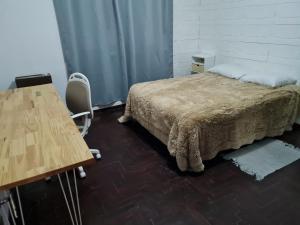 a bedroom with a bed and a desk and a table at Casa a minutos del Aeropuerto in Ezeiza