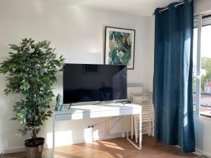 uma secretária branca com uma televisão e uma planta num quarto em Summer in Paris em Ivry-sur-Seine