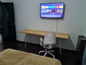 escritorio con silla y TV en la pared en Casa a minutos del Aeropuerto en Ezeiza