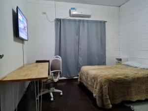 a bedroom with a bed and a desk and a window at Casa a minutos del Aeropuerto in Ezeiza