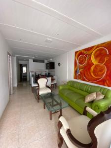 ein Wohnzimmer mit einer grünen Couch und einem Gemälde in der Unterkunft apto caney 301 in Cali