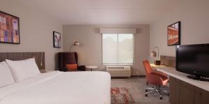 Hilton Garden Inn Atlanta Airport/Millenium Center في أتلانتا: غرفة نوم بسرير ومكتب وتلفزيون