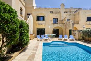 una piscina di fronte a una casa con sedie e tavolo di Dar ta' Censina Villa with Private Pool a Għasri