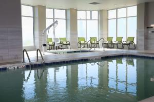 a swimming pool with chairs in a building at Hilton Garden Inn Arvada/Denver, CO in Arvada