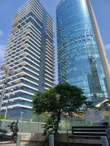 zwei hohe Gebäude in einer Stadt mit Bank und Baum in der Unterkunft studio mirel 4 in Tel Aviv