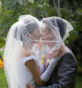 una novia y un novio besándose bajo su velo en Homewood Suites by Hilton Bloomington, en Bloomington