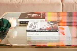 três livros numa mesa de vidro com uma vela em Stadtflucht Loft 3.1.1 em Berlim