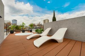 2 sillas blancas sentadas en una terraza de madera en Fliphaus Honduras 5750 - Lux 3 Bd Palermo H en Buenos Aires